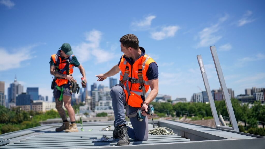Contacto Reformas JM Portugalete Construction workers wearing safety gear are on a rooftop.